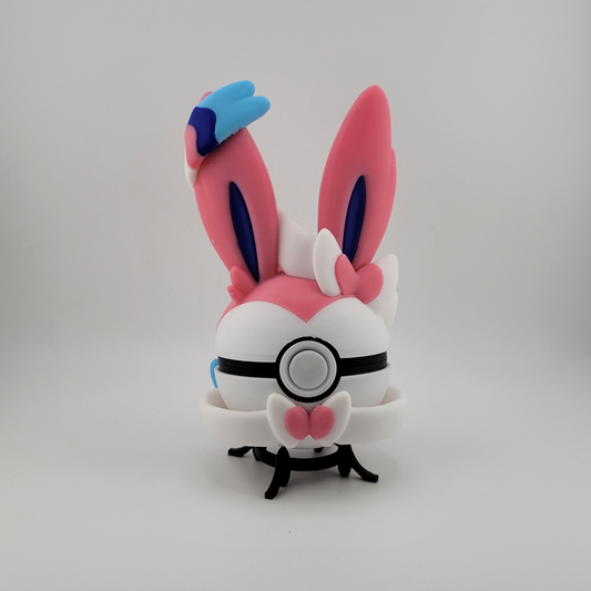 Sylveon-themed pink and white Pokéball with ears and ribbon details, 3D printed collectible display.