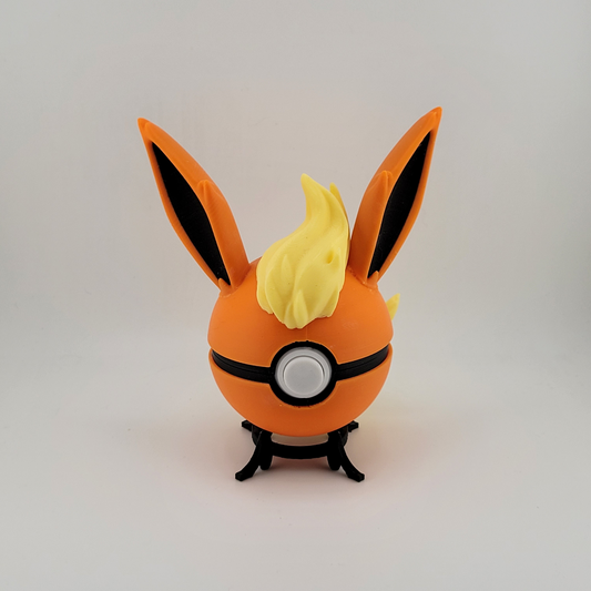 Flareon Pokeball with orange and yellow design featuring ears and tuft, displayed on a stand.