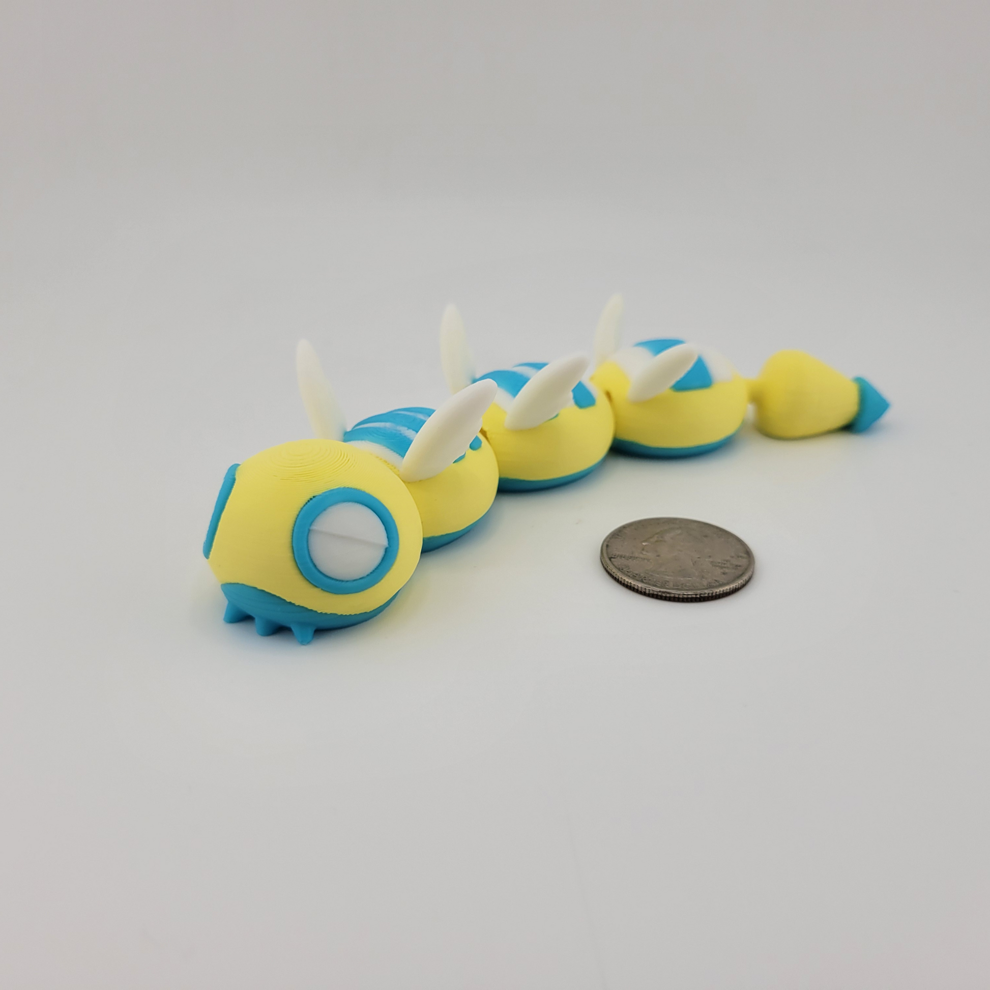 3D printed Dudunsparce Pokemon figure with flexible joints, shown with a coin for size reference.
