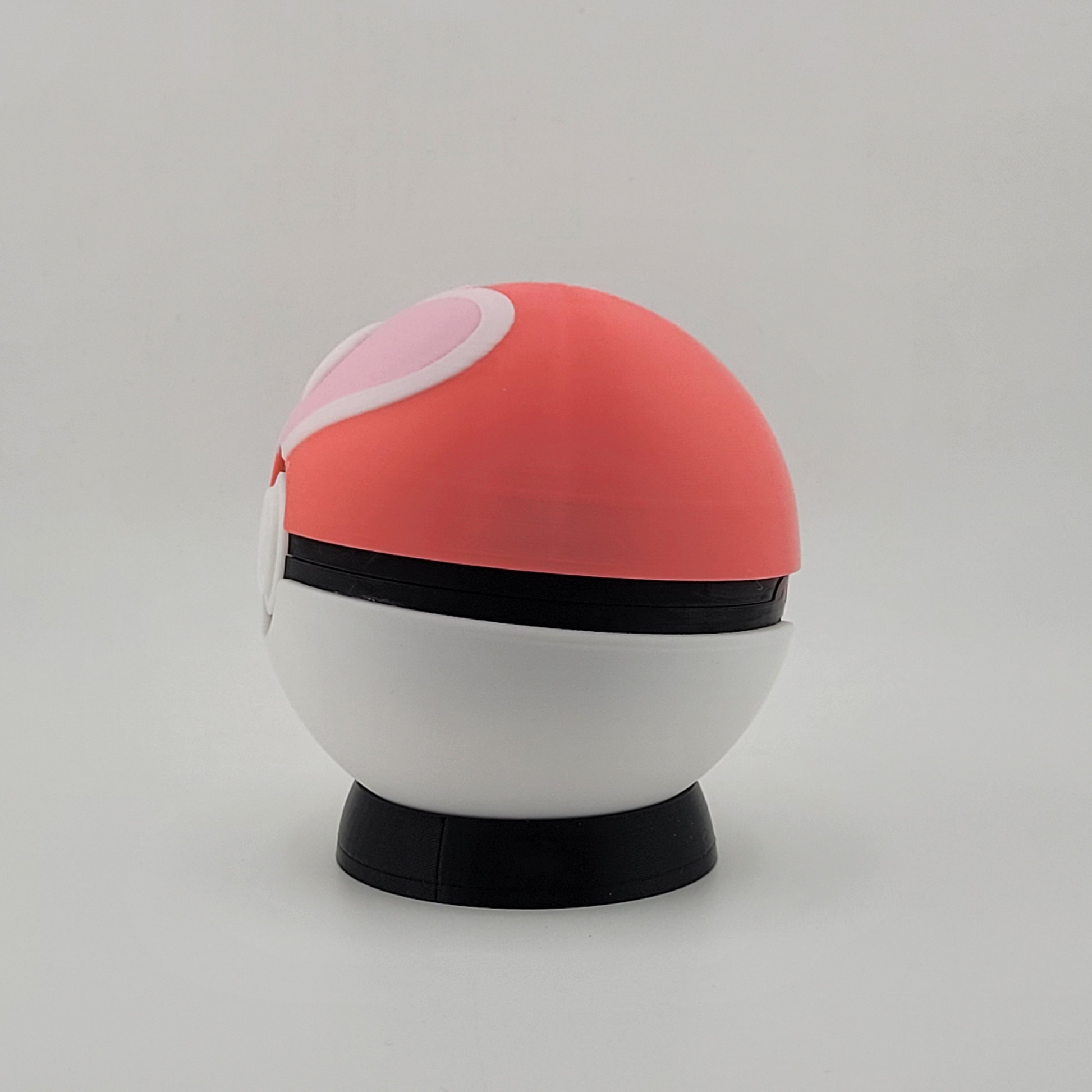 3D printed Loveball with pink and white design, heart center, displayed on stand.