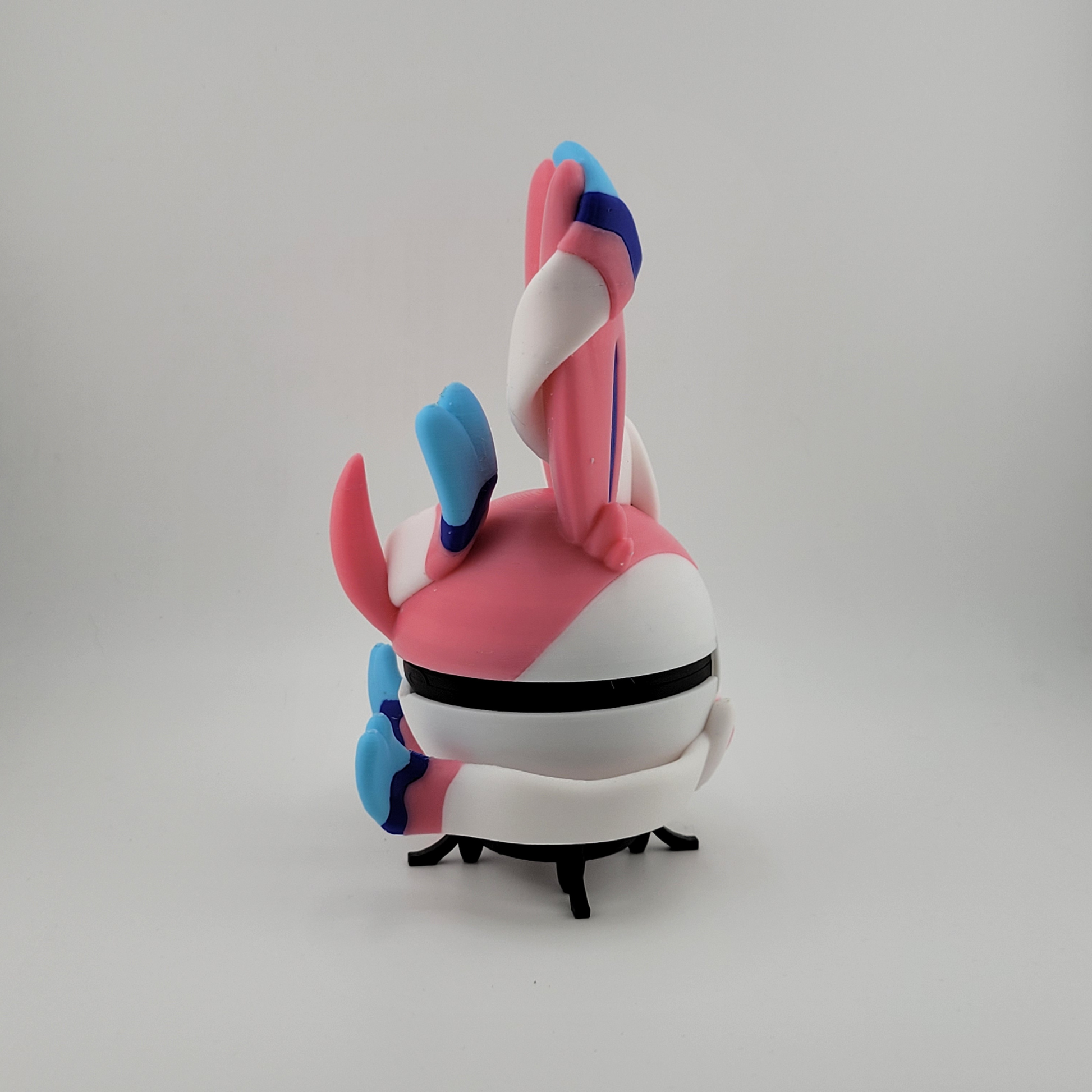 3D printed Sylveon-themed Pokéball with pastel pink, blue, and white colors and ribbon motifs, functional collectible storage.