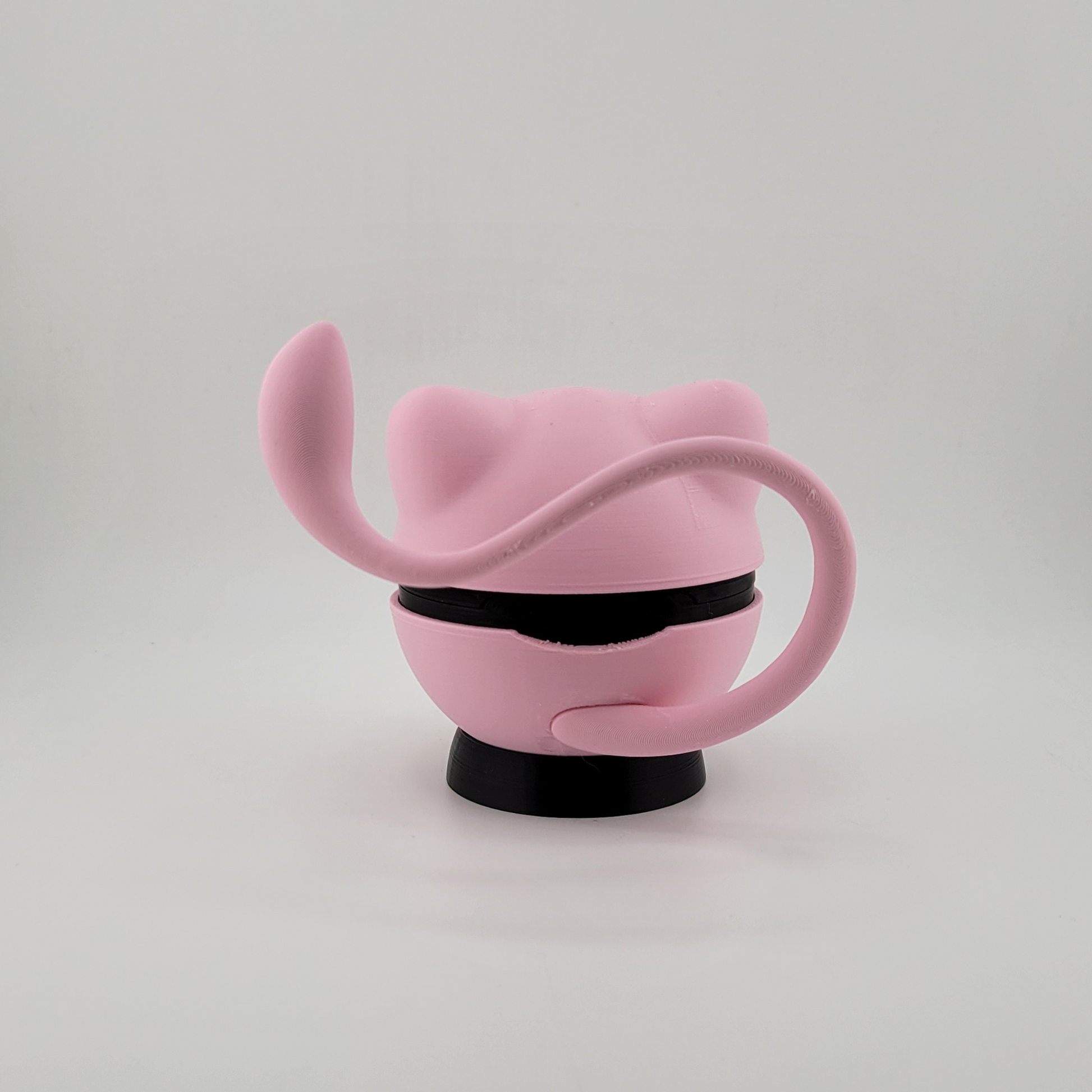 Pink Mew-themed Pokéball with tail and sleek design, made from PLA plastic.