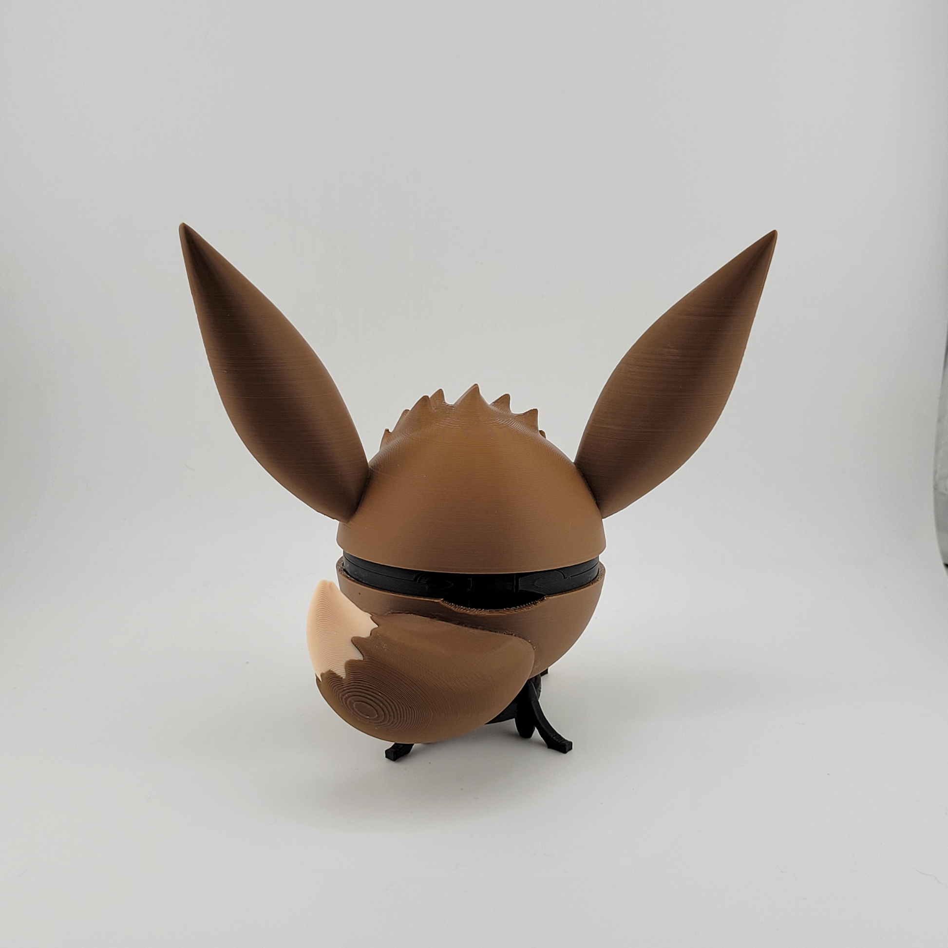 3D printed Eevee-themed Pokéball with brown and cream colors, featuring large ears and a tail, hand-assembled with durable PLA plastic.