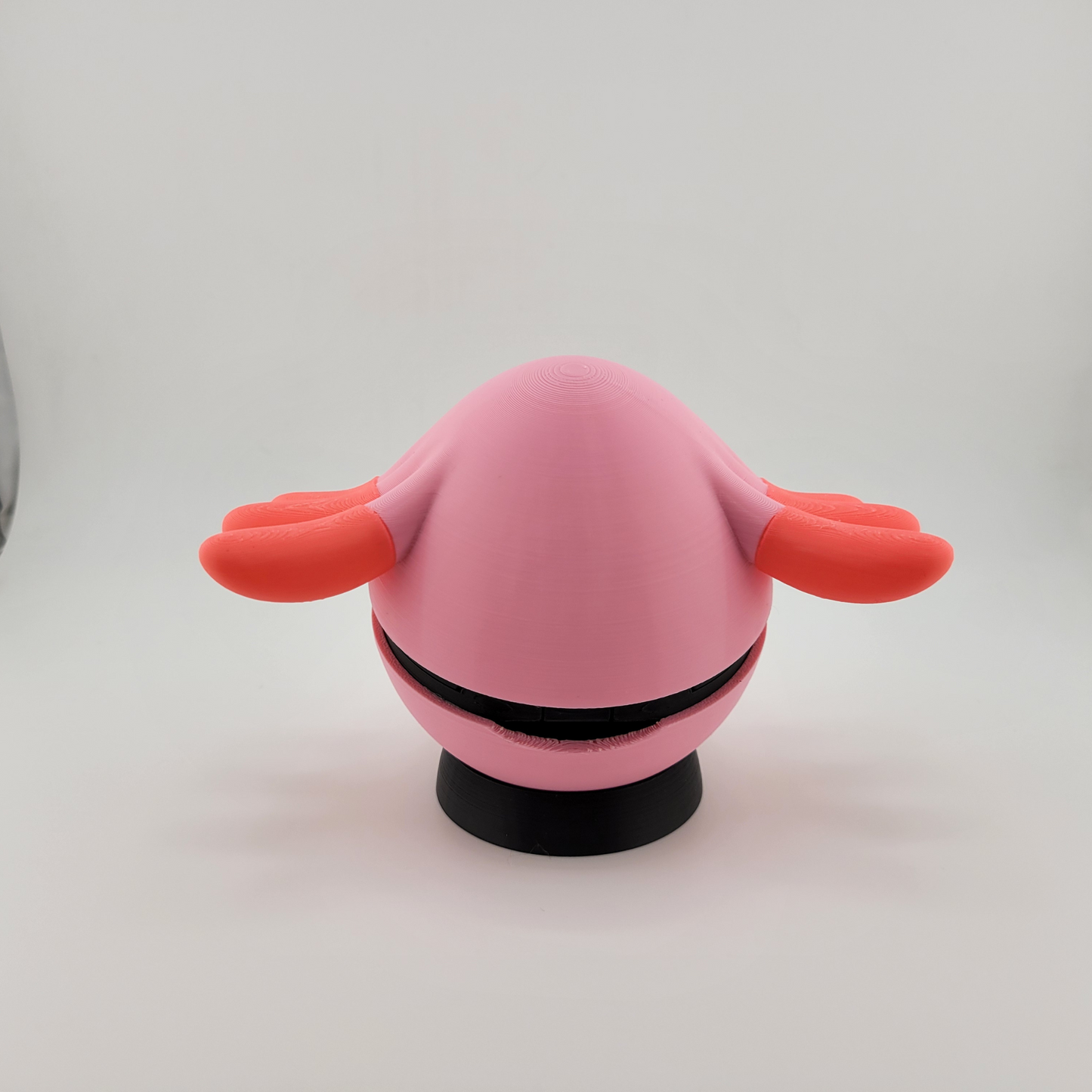 3D printed Chansey-themed Pokeball figurine in pink with orange wings and black base, handcrafted collectible inspired by Pokémon.