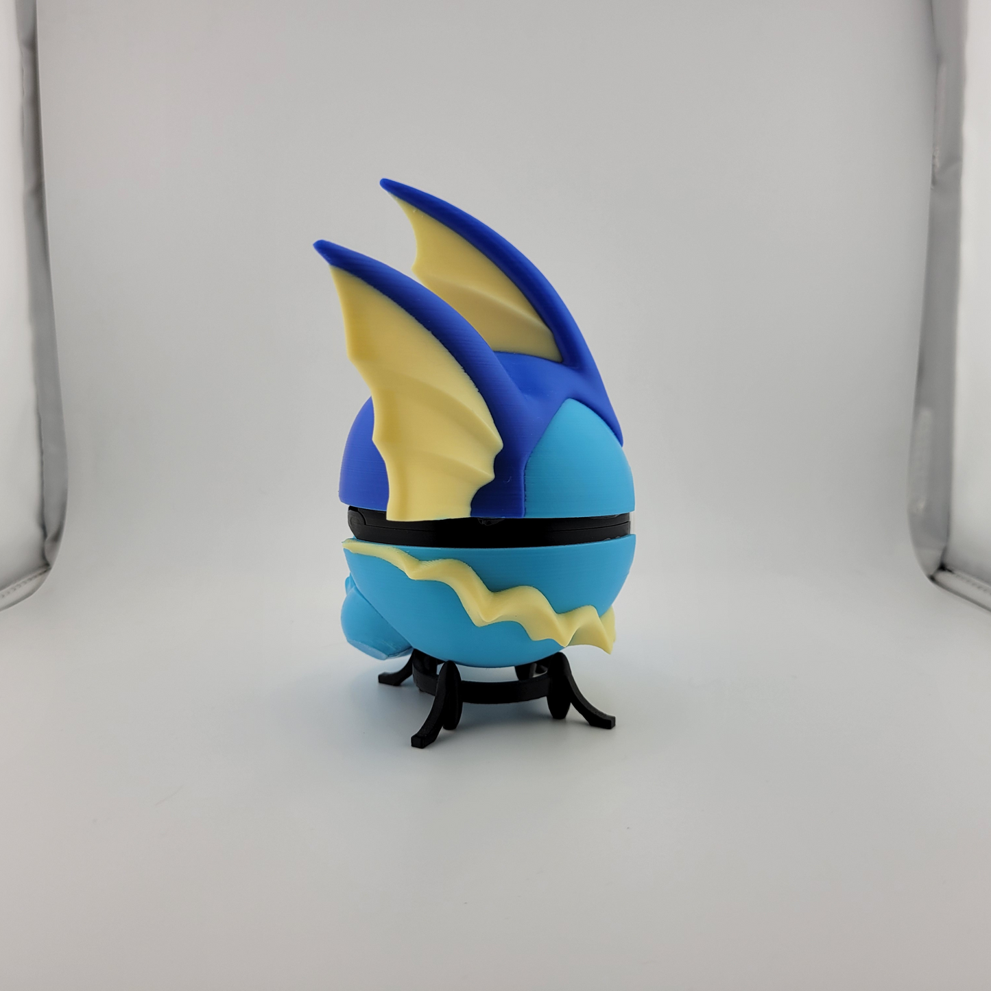3D printed Vaporeon Pokeball toy in blue and yellow with display stand.