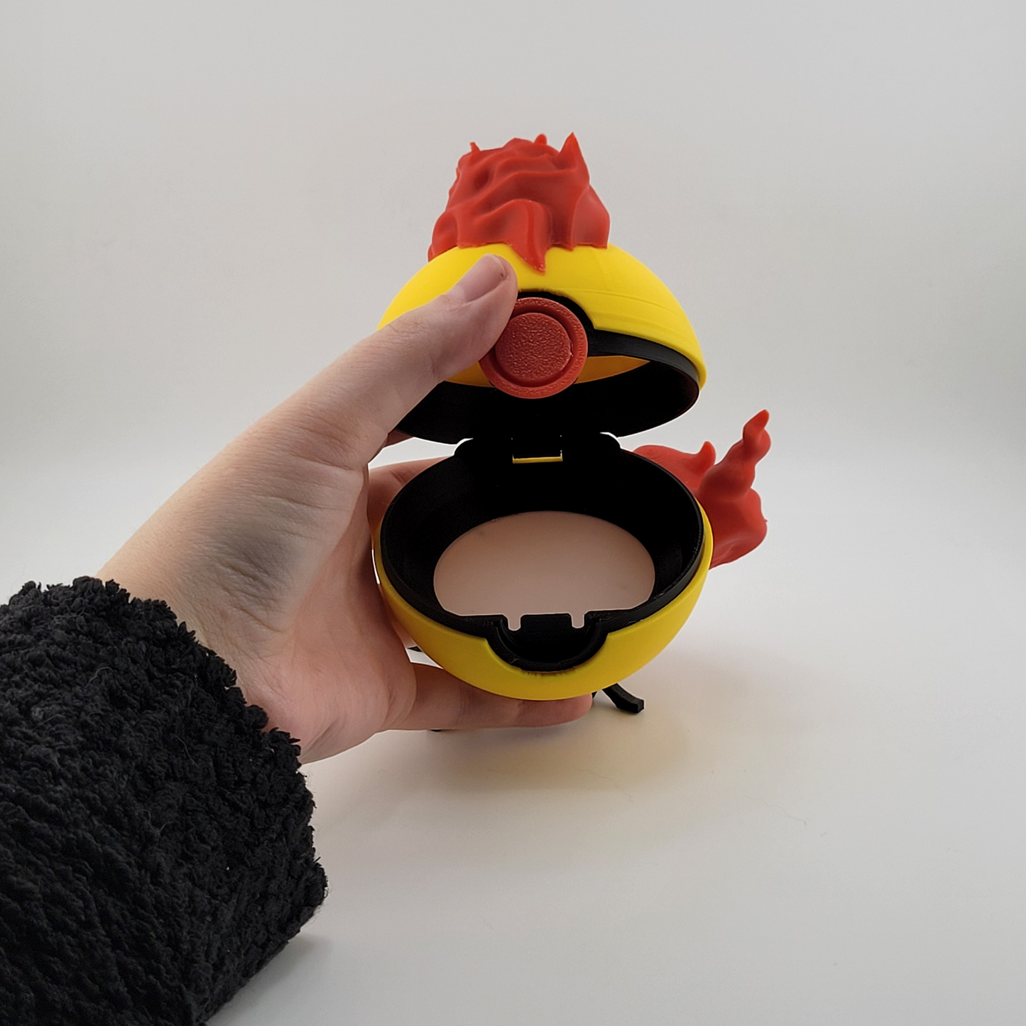 3D printed Moltres Pokeball with fiery design held in hand.