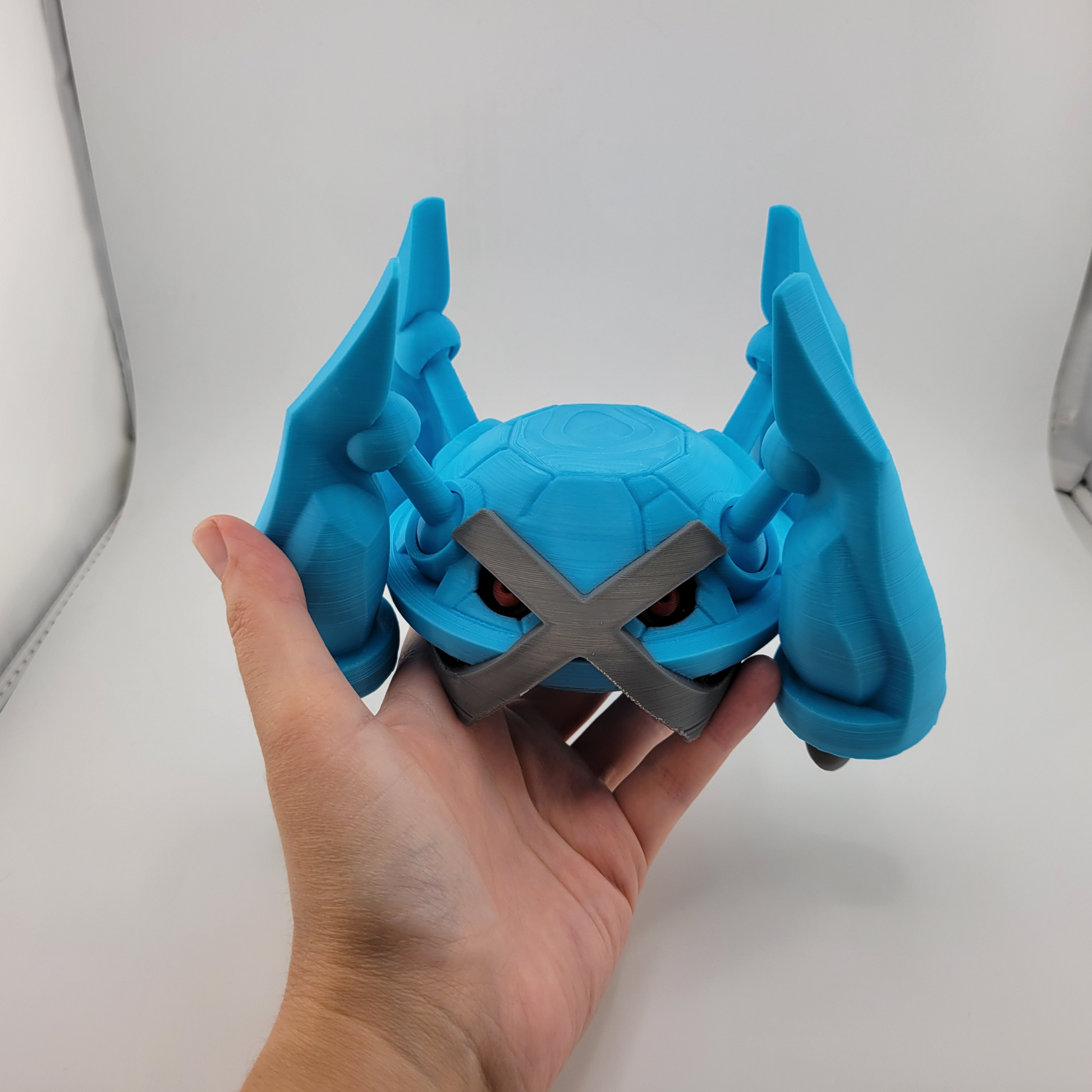 3D printed Metagross toy with articulated blue limbs and silver cross detail.