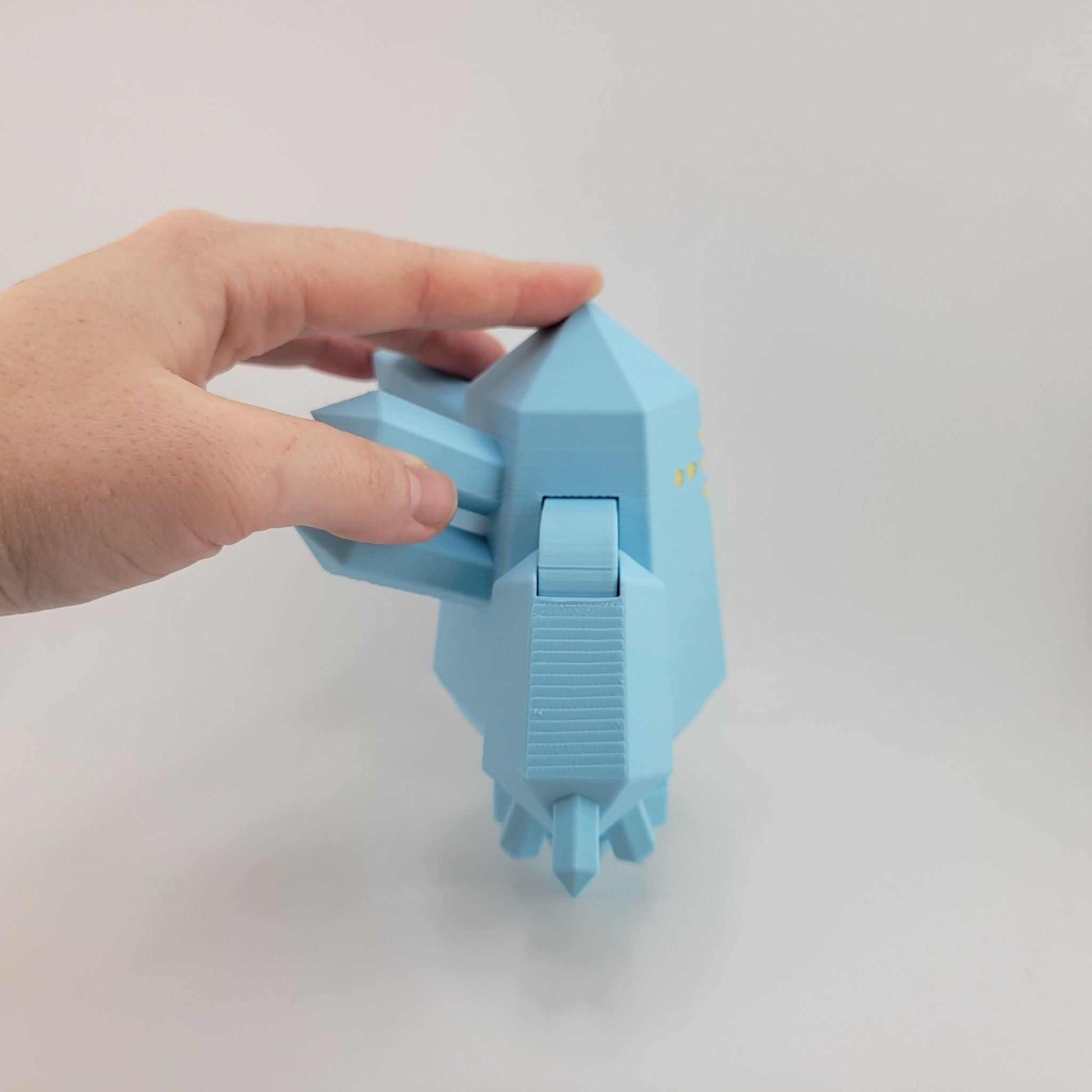 Hand holding a small blue 3D printed poseable Regice figure from Pokémon with geometric icy design