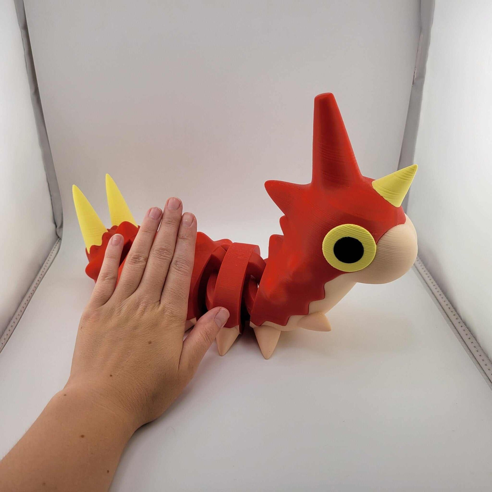 Life-sized articulated Wurmple Pokémon figurine in red and yellow, 12 inches long, hand-assembled 3D printed PLA plastic model with poseable segments.