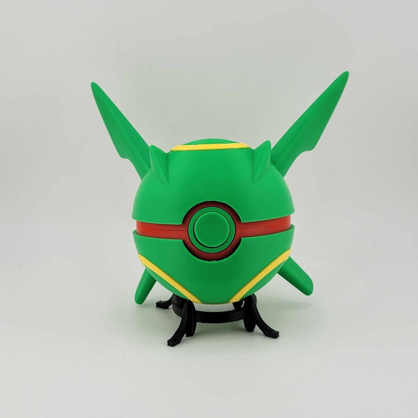 Green and yellow 3D printed Rayquaza Pokeball with red button and pointed ears on black stand
