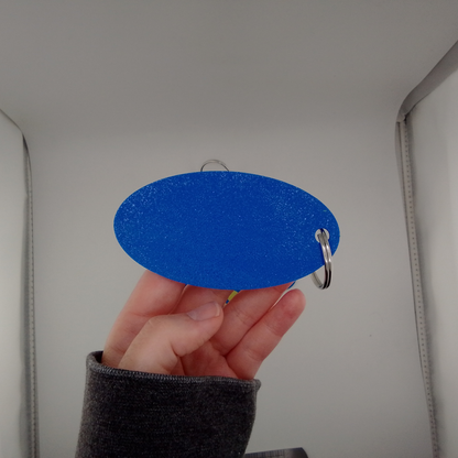 Hand holding a blue oval object with a keyring against a neutral background
