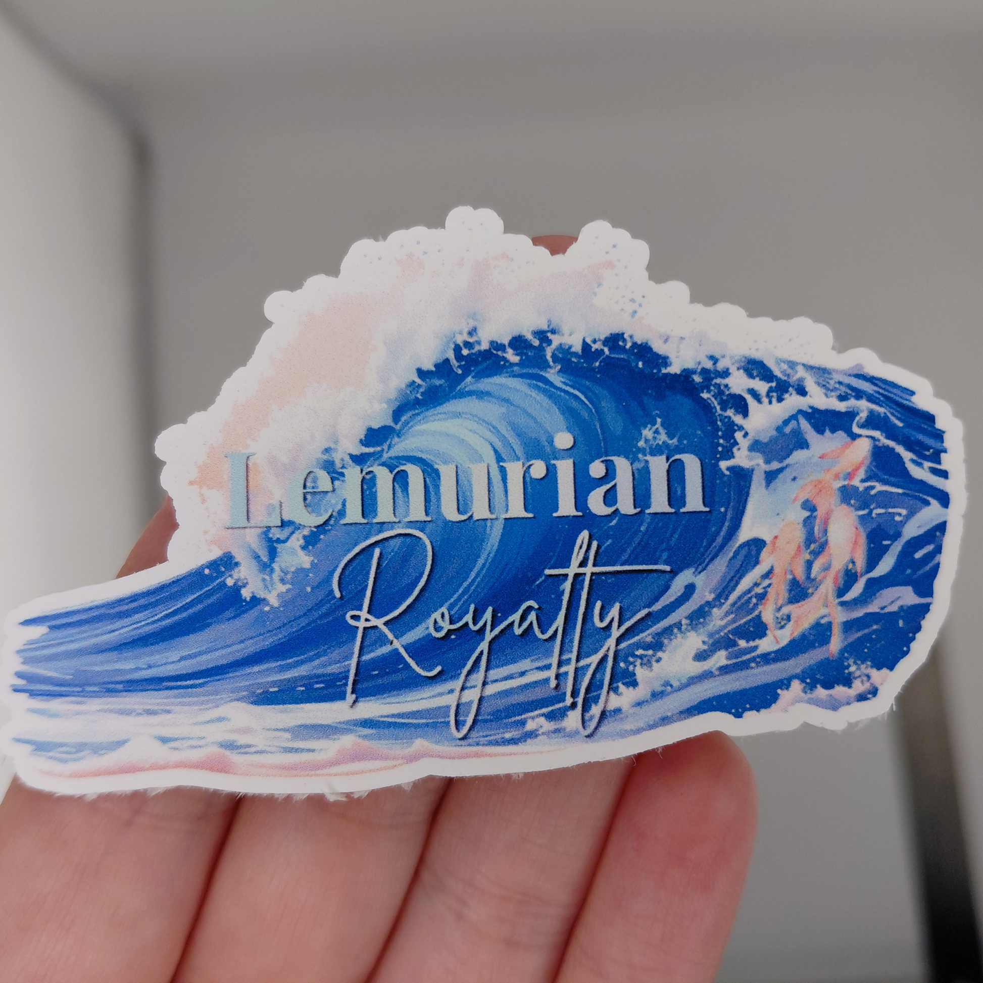 Love and Deepspace Rafayel Lemurian Royalty vinyl sticker featuring a large ocean wave in shades of blue with soft pink accents and elegant typography. Anime-inspired waterproof decal perfect for laptops, water bottles, journals, gaming accessories, and otome game collections. Aesthetic ocean-themed sticker designed for fans of Rafayel and Love and Deepspace.