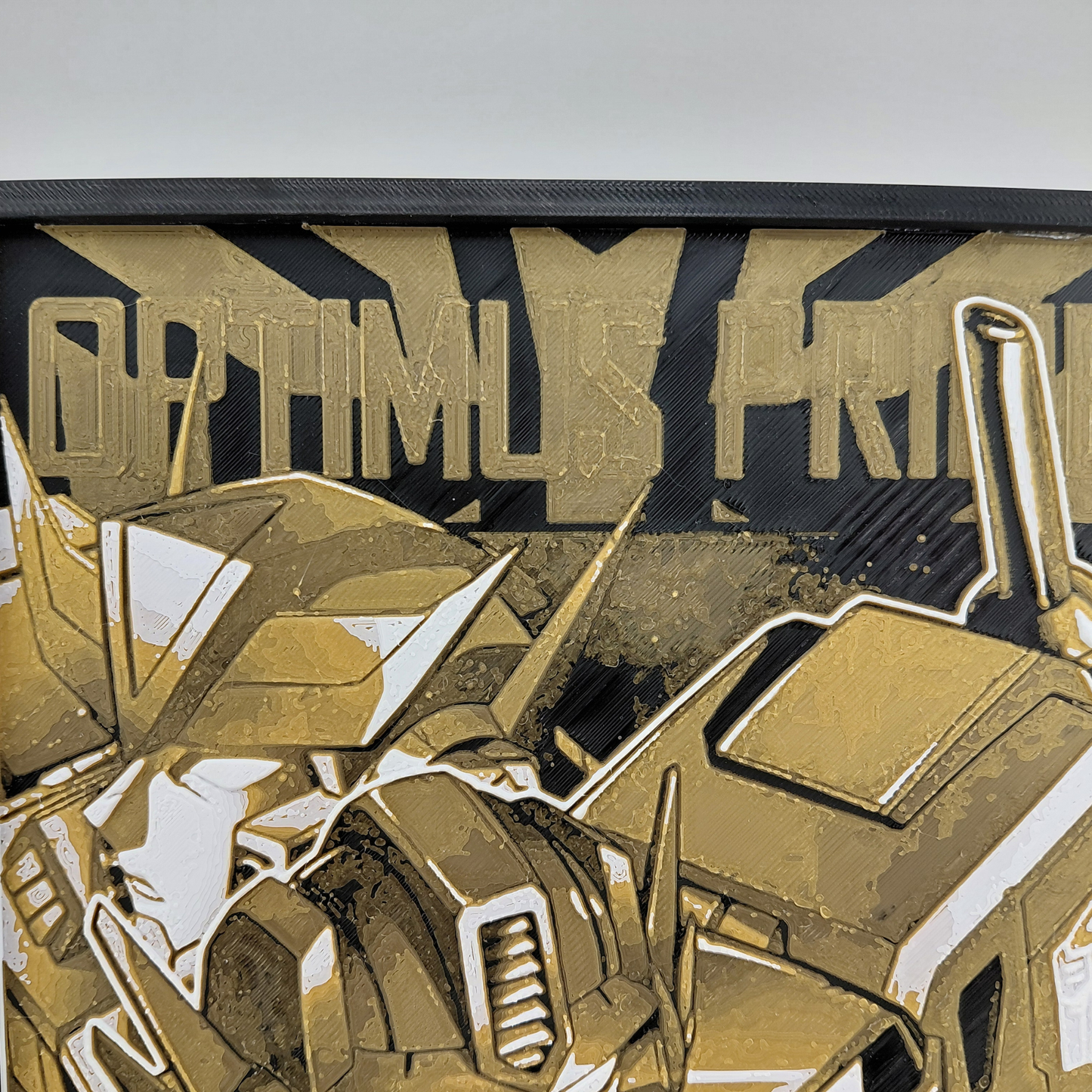 Layered 3D printed Optimus Prime wall art inspired by a classic Transformers comic cover. Created using Chroma Canvas technology with textured depth, lightweight PLA construction, black frame, and gold, black, and white color palette. Can be displayed on a desk using the built-in stand or hung on a wall. Ideal for Transformers collectors, comic fans, gaming rooms, and nerd office décor.
