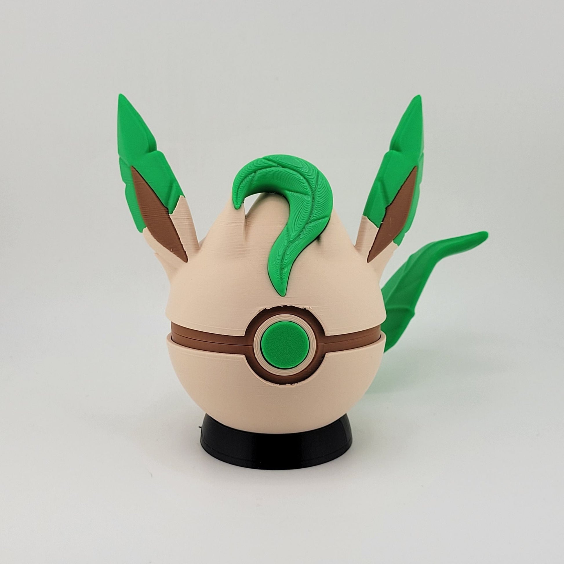 3D printed Leafeon-themed functional Pokeball with green leaf accents and beige base on a black stand